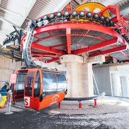 3S-Bahn, Skigebiet Kitzbühel – Moderne Gondelbahn mit markant rotem Design, während sich Skifahrer auf den Einstieg vorbereiten.