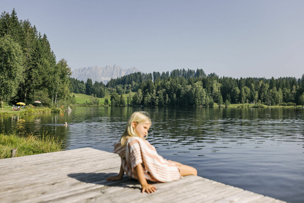 Kleines Mädchen sitzt am Ufer des Schwarzsee