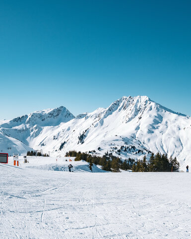 Blick von der Bärenbadalm, Skigebiet Kitzbühel, verschneite Berglandschaft unter klarem, blauem Himmel.