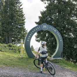 Ein weißer Flurbereich mit einer offenen Garderobe, Kissen und einem kleinen schwarzen Schild