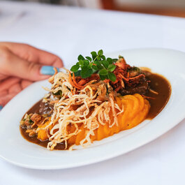 Ein weißer Flurbereich mit einer offenen Garderobe, Kissen und einem kleinen schwarzen Schild