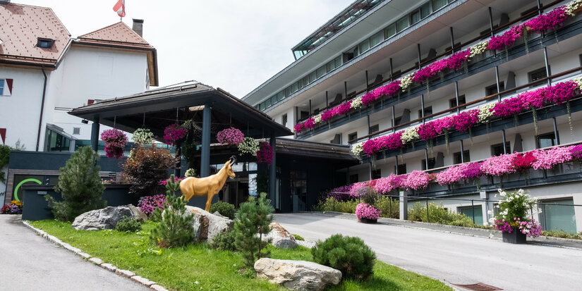 Hotel Lebenberg Schlosshotel Kitzbühel mit Balkonpflanzen und Steinbock-Statue.