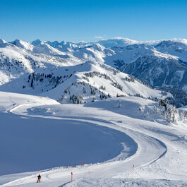 Kitzbüheler Horn, Skigebiet Kitzbühel, Skifahrer fährt über präparierte Piste in winterlicher Berglandschaft.