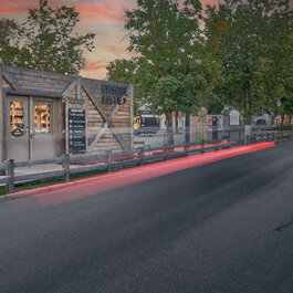 Ein malerisches Holzgebäude an einer ruhigen Straße, umgeben von Natur, das eine friedliche Stimmung ausstrahlt.