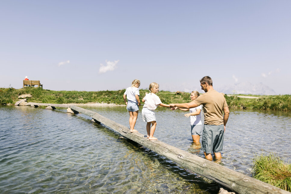 Ein weißer Flurbereich mit einer offenen Garderobe, Kissen und einem kleinen schwarzen Schild
