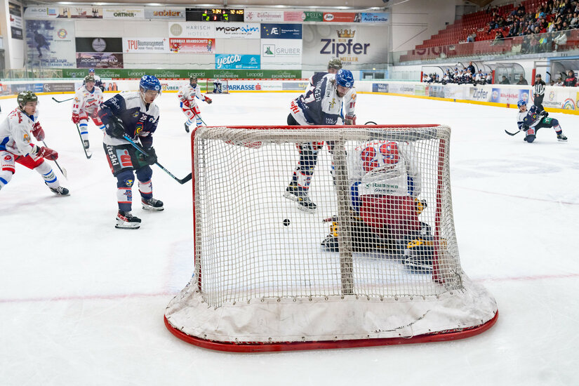 Ein spannendes Eishockeyspiel in Kitzbühel, bei dem ein Spieler der Kitzbüheler Adler auf das Tor zielt, während der Torwart bereit ist, den Schuss abzuwehren.