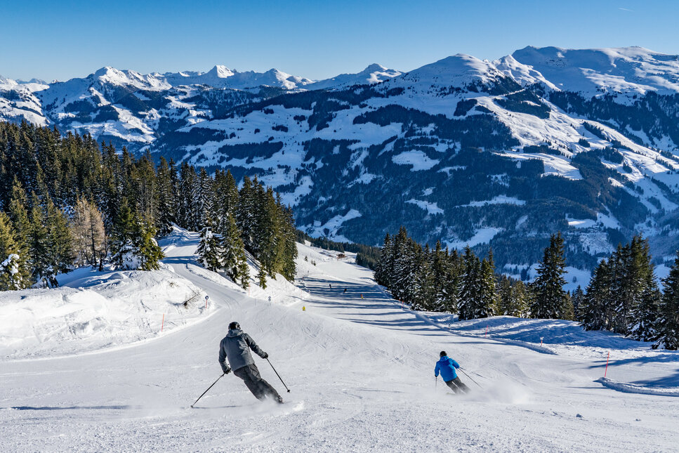 2 Skifahrer fahren runter auf eine Piste in Jochberg