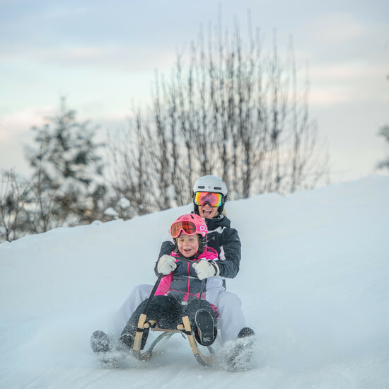 Mutter und Tochter haben Spaß beim Rodeln in Kitzbühel
