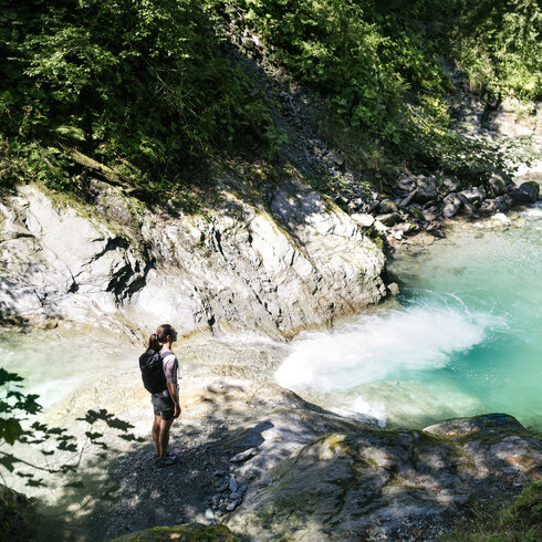 Ein weißer Flurbereich mit einer offenen Garderobe, Kissen und einem kleinen schwarzen Schild