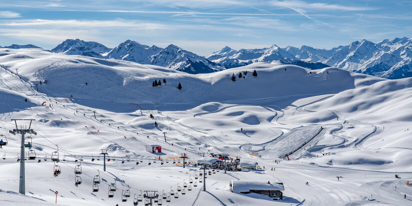 Kitzbüheler Horn, Skifahrer auf verschneiten Pisten vor Bergkulisse.