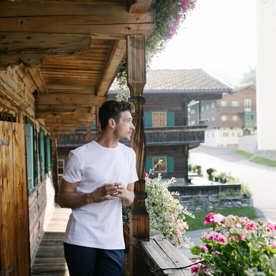 Ein junger Mann steht auf einem urigen Balkon in Kitzbühel