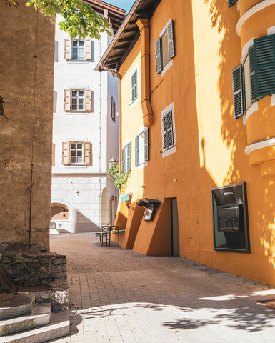 Ein Tisch steht in der Gasse, während die bunten Fassaden der Gebäude im Hintergrund eine lebendige Kulisse bieten.