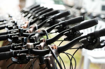 A series of bicycle handlebars is shown in close view. The handlebars are clearly visible and display the details of the brake and shifting mechanisms.