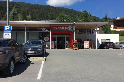 Spar Supermarkt Jochberg Eingangsbereich eines Spar-Supermarktes mit Parkplatz und bewaldetem Berg im Hintergrund.
