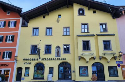 A colorful, yellow building with a classic facade. Below it is a sign that reads "City Pharmacy".