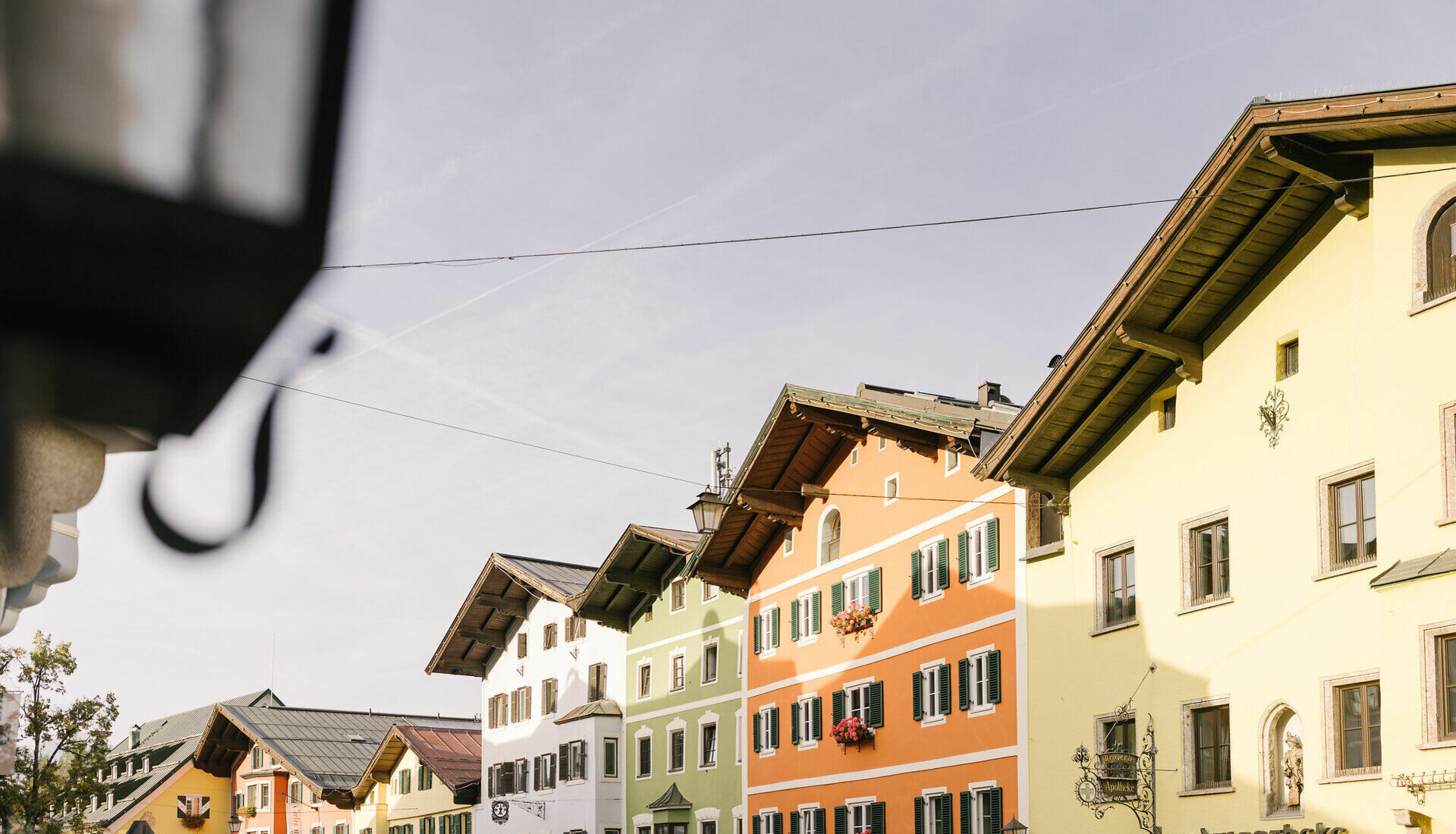 Bunte Fassaden von Gebäuden in einer malerischen Stadt, die im Herbstlicht erstrahlen und eine einladende Atmosphäre schaffen.
