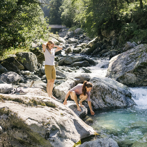 Ein weißer Flurbereich mit einer offenen Garderobe, Kissen und einem kleinen schwarzen Schild
