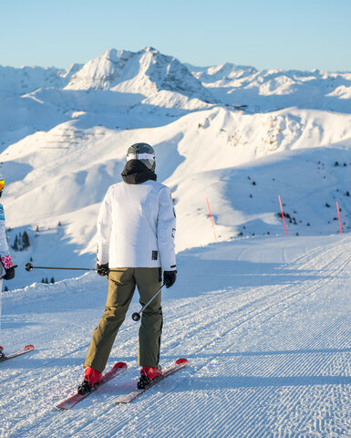 Steinbergkogel, Skigebiet Kitzbühel, zwei Skifahrer auf verschneiter Piste mit Blick auf die Berglandschaft.