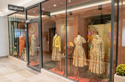 A shop window with stylish dresses made from colorful fabrics. The mannequins are elegantly displayed and showcase the latest fashion trends.