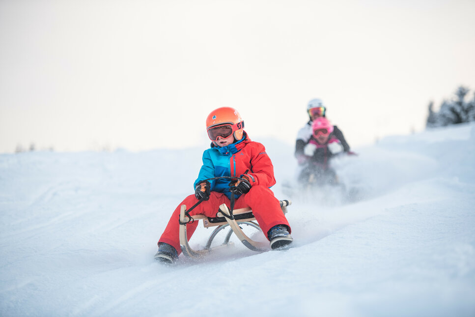 Eine Familie rodeln runter auf ein Hang