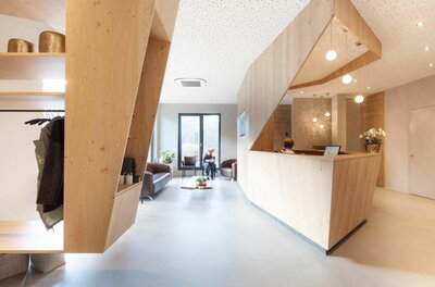 A modern reception area with wood decor and a cozy seating area. Soft light and an inviting atmosphere create a friendly ambiance.