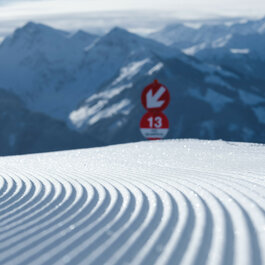 Die glitzernde Schneedecke erstreckt sich bis zum Horizont, während die schneebedeckten Berge eine beeindruckende Kulisse bilden.
