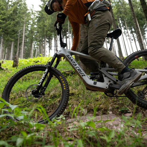 Ein weißer Flurbereich mit einer offenen Garderobe, Kissen und einem kleinen schwarzen Schild
