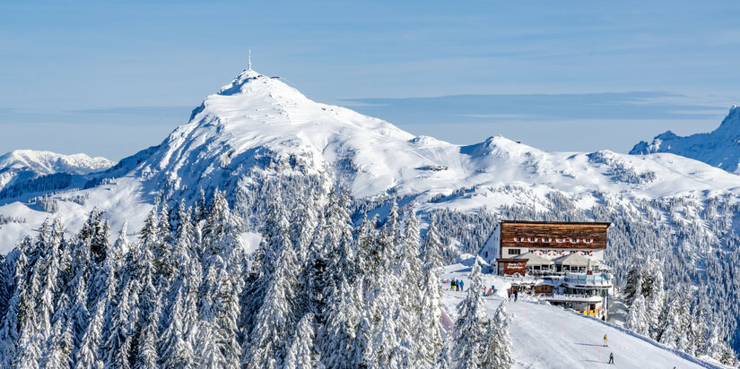 Hahnenkamm, Skigebiet Kitzbühel, verschneite Berglandschaft mit Berghütte und Tannenbäumen.