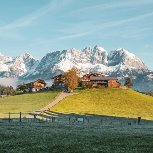 Ein weißer Flurbereich mit einer offenen Garderobe, Kissen und einem kleinen schwarzen Schild