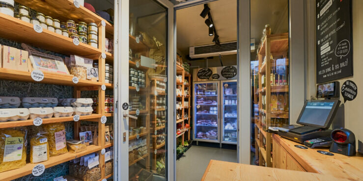 Ein einladender Lebensmittelladen mit Regalen voller Gläser, Dosen und Trockenwaren, die sorgfältig angeordnet sind.