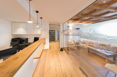 A modern reception area with a wooden counter and bright walls. The room is well-lit and has a cozy seating area.
