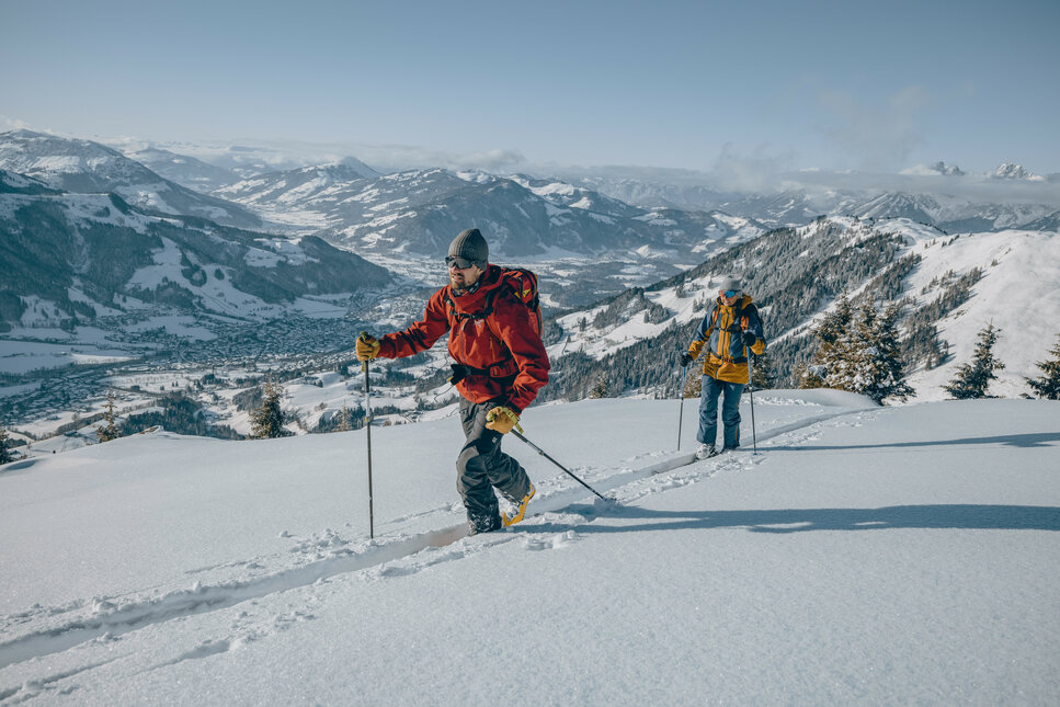 Skitouren Bichlalm, Skigebiet Kitzbühel, zwei Skitourengeher beim Aufstieg in verschneiter Berglandschaft.