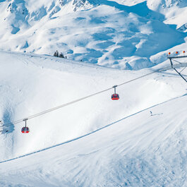 Rote 3S-Bahn im Skigebiet Kitzbühel über verschneiter Berglandschaft.
