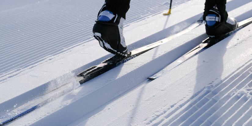 Beim Langlauf in Kitzbühel gleitet ein Langläufer über frisch präparierte Loipe im strahlenden Sonnenlicht.