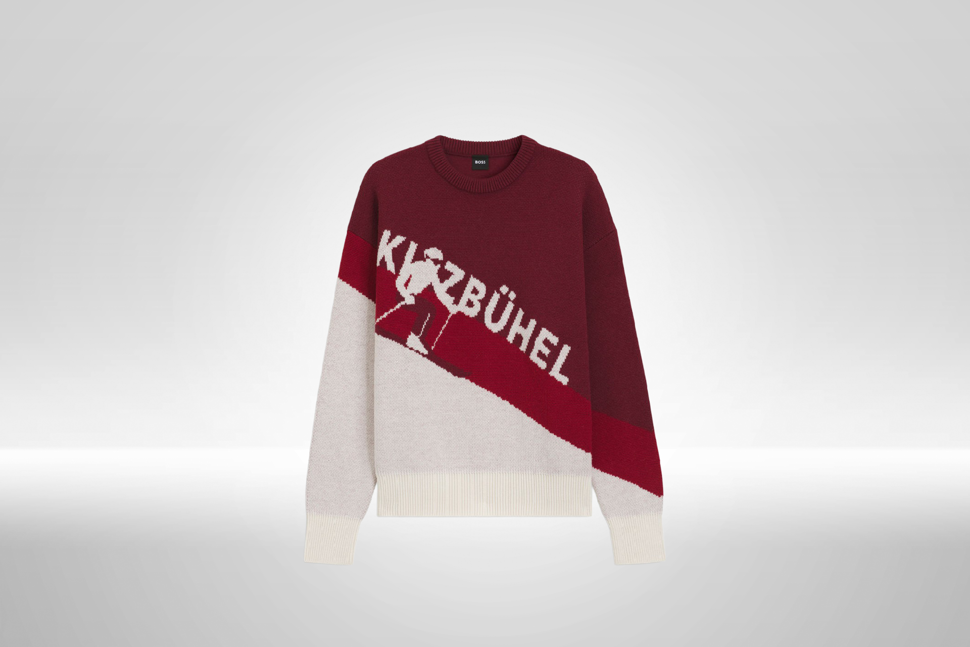 Ein stilvoller Pullover in Rot und Beige mit dem Schriftzug 'Kitzbühel' und einem Skifahrer-Motiv auf der Vorderseite.