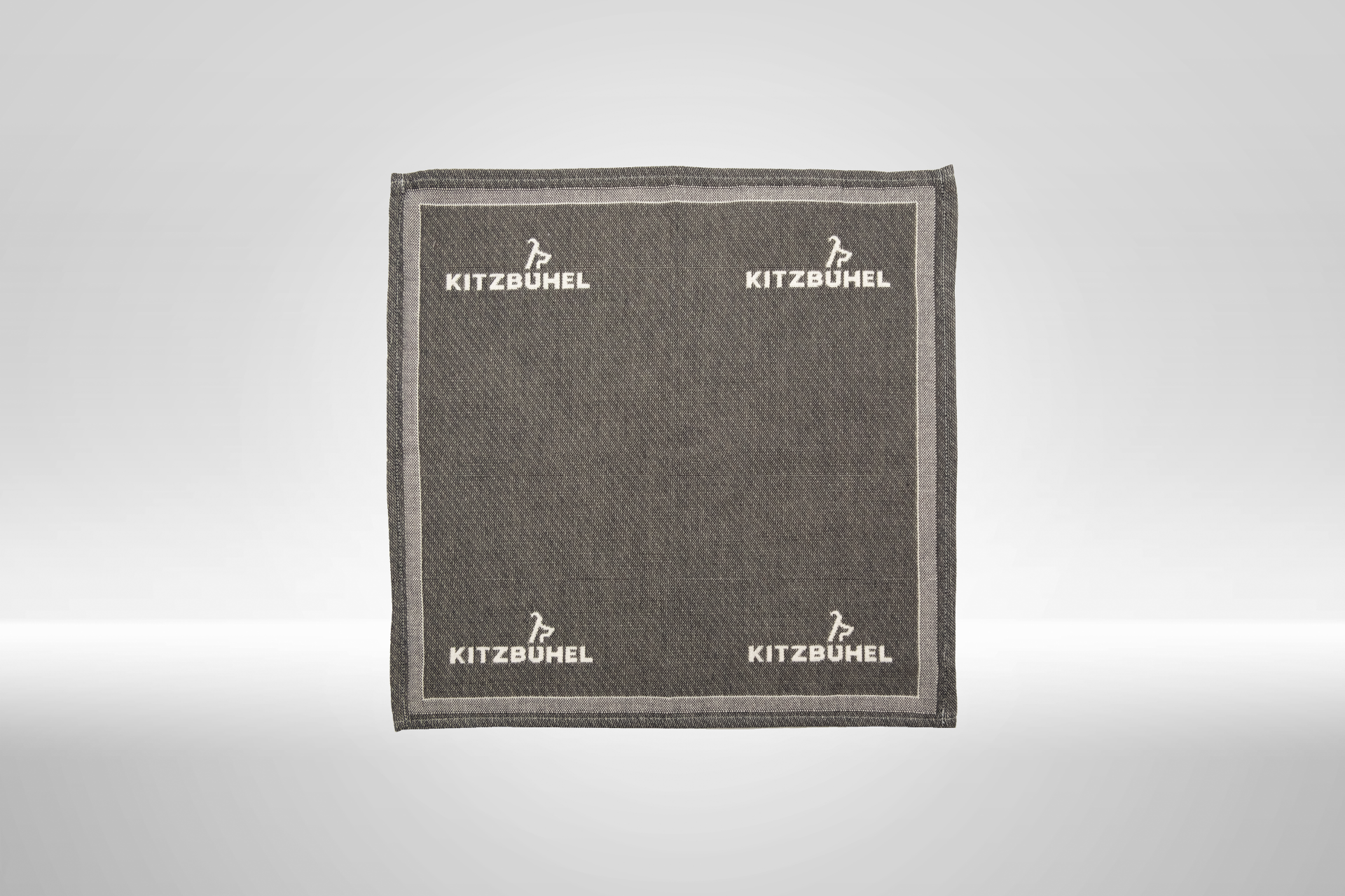 Eine graue Stoffserviette mit dem Logo von Kitzbühel, elegant und schlicht, ideal für festliche Anlässe oder den Alltag.